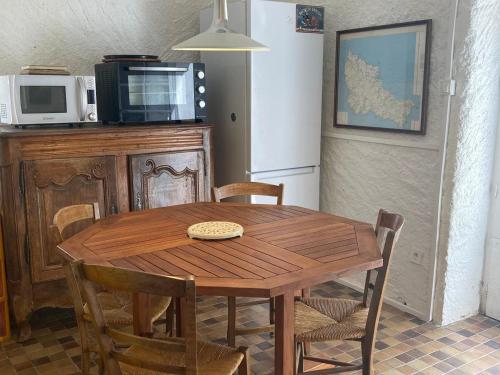 - une table et des chaises en bois dans une cuisine équipée d'un four micro-ondes dans l'établissement Maison cosy à Locmaria, 6 pers, 1 km plage, grand jardin, animaux ok - FR-1-418-256, à Locmaria