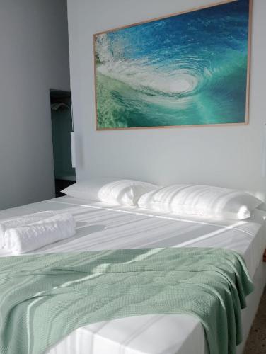 a white bed with a picture on the wall at ELEVATE - Uluwatu, Bali in Uluwatu
