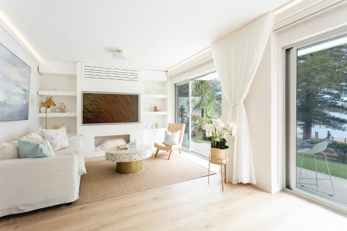 a living room with a couch and a tv at 3 Bedroom Beachfront Manly Garden Apartment in Sydney