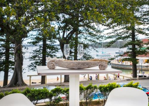 a table with a plate of food and wine glasses at 3 Bedroom Beachfront Manly Garden Apartment in Sydney