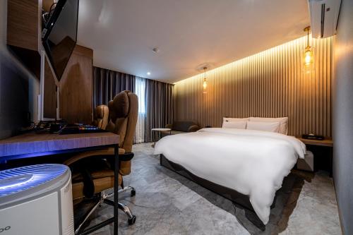 a hotel room with a large white bed and a desk at 충주 어반브라운호텔 in Chungju