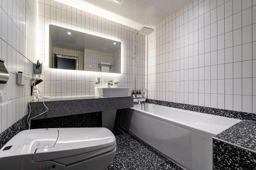 a bathroom with a toilet and a tub and a sink at 충주 어반브라운호텔 in Chungju