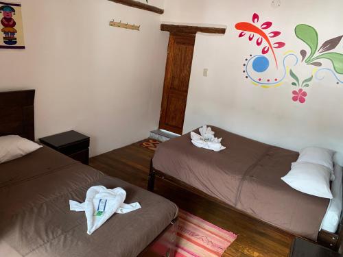 a room with two beds and a colorful wall at Casa Patacalle in Ollantaytambo
