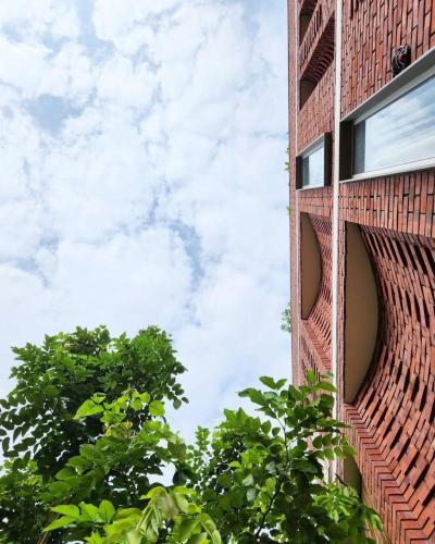 a red brick building with trees in the foreground at Saur Homestay in Jaipur