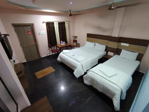 a hotel room with two beds and a table at Sri Murugan Beach Paradise Hotel in Mahabalipuram