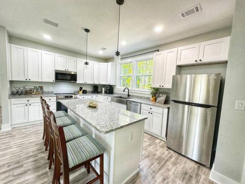 a kitchen with white cabinets and a stainless steel refrigerator at Seabrook Coastal Cottage - Beaufort Parris Island in Seabrook