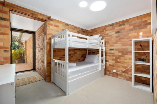 a room with two bunk beds in a brick wall at Sunset House on the Hill in Kingscliff