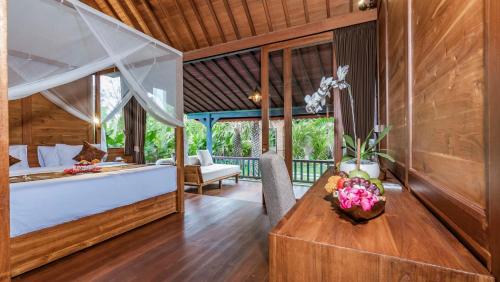 a bedroom in a villa with a bed and a table at The Puspa Villa in Sukawati