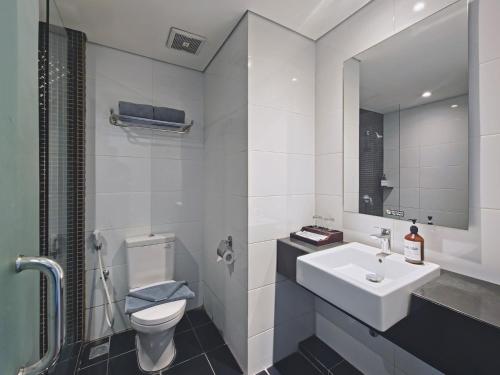 a white bathroom with a sink and a toilet at Luminor Hotel Jemursari By WH in Surabaya
