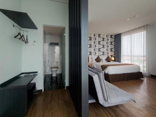 a bedroom with a bed and a desk and a television at Luminor Hotel Jemursari By WH with The Best Breakfast in Town and Located Near Surabaya Industrial Estate Rungkut SIER in Surabaya