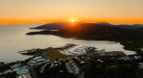 an aerial view of a city with the sun setting over a lake at Azure Sea Whitsunday Resort in Airlie Beach