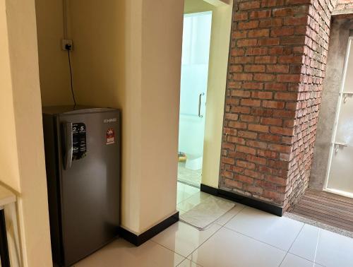 a silver refrigerator in a room with a brick wall at Nibong Tebal Studio Home Stay in Nibung Tebal