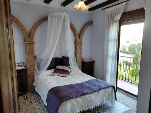 Un dormitorio con cama con dosel y balcón. en Villa el Membrillar, en Priego de Córdoba
