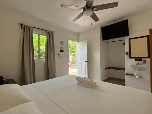a bedroom with a white bed and a ceiling fan at La Diosa Kali Beach Front Hotel in Holbox Island