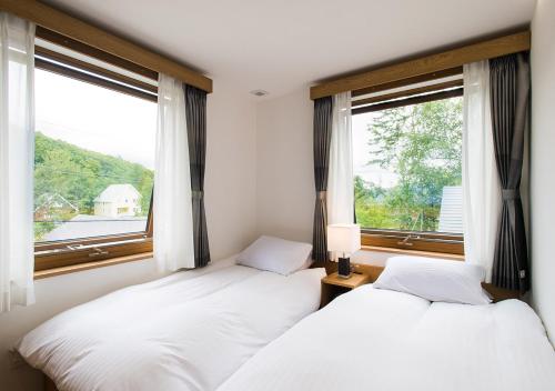 two beds in a room with two windows at NISEKO REISE HOUSE ニセコライゼハウス in Kutchan