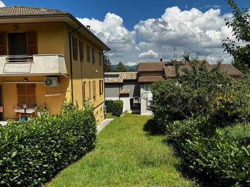 a yellow house with a green yard with bushes at Apartment in Esanatoglia near Apennines Trails in Esanatoglia