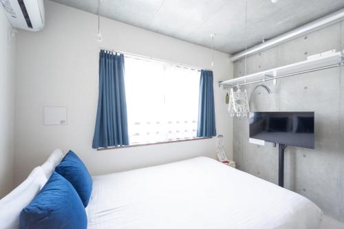 a bedroom with a bed with blue pillows and a window at Ferio Kamata II in Tokyo