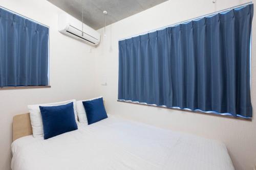a room with a bed with blue curtains at Ferio Kamata II in Tokyo