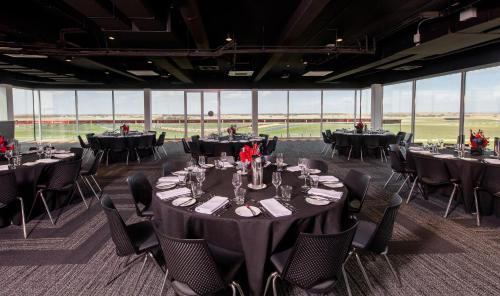 a banquet hall with tables and chairs and windows at Rydges Pit Lane in Tailem Bend