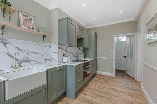 Una cocina con gabinetes verdes y un fregadero. en Monument House Horncastle, en Lincolnshire