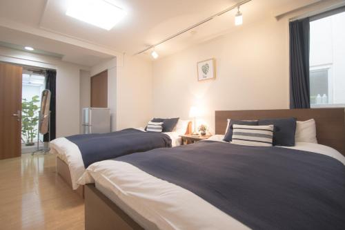 a bedroom with two beds with blue and white sheets at ELIF-Nakasu- in Fukuoka