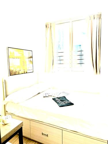 a white bedroom with a bed with a window at 木居 Woody House in Hong Kong