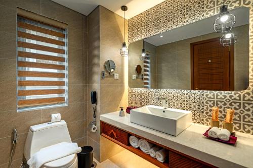 a bathroom with a sink and a toilet and a mirror at The Saga Hotel Hoi An in Hoi An