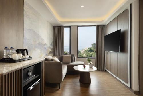 a living room with a couch and a table and a tv at Hotel Santika Premiere Lampung in Bandar Lampung