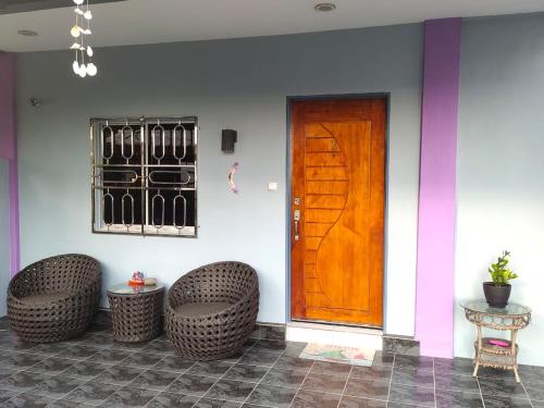 a room with a wooden door and two wicker chairs at OCEAN LODGE in Pantai Cenang