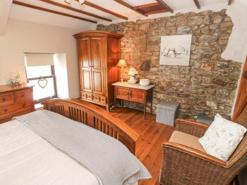 a bedroom with a bed and a stone wall at Inglenook Cottage in Haverfordwest