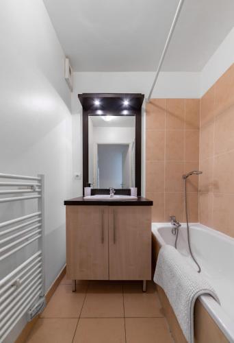 une salle de bain avec un lavabo, une baignoire et un miroir dans l'établissement L'Eugenie - Appartement design & confort en centre-ville, à Vichy