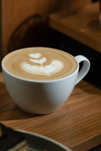 a cup of coffee sitting on a wooden table at Hotel Santika Premiere Lampung in Bandar Lampung