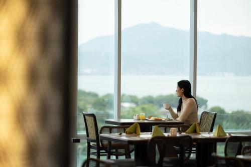 a woman sitting at a table in a restaurant at Hotel Santika Premiere Lampung in Bandar Lampung