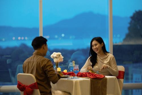a man and woman sitting at a table in a restaurant at Hotel Santika Premiere Lampung in Bandar Lampung