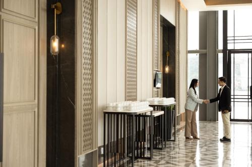 a man and woman shaking hands in a lobby at Hotel Santika Premiere Lampung in Bandar Lampung
