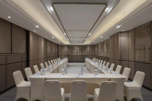 a conference room with a long table and white chairs at Hotel Santika Premiere Lampung in Bandar Lampung