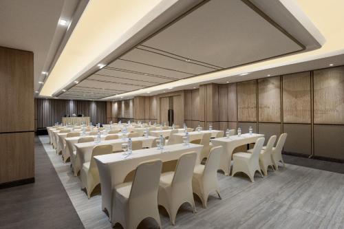 a conference room with white tables and white chairs at Hotel Santika Premiere Lampung in Bandar Lampung