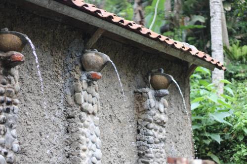 a stone wall with two water faucets on it at Arnata Guest House & Pasraman Yoga Lokanata in Bangli