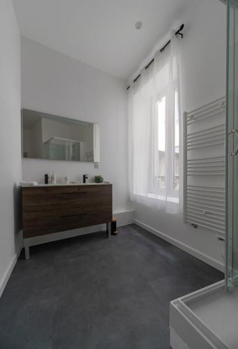 une salle de bain blanche avec un lavabo et un miroir dans l'établissement Le Ravy - Appartement design, 2 chambres, centre ville, à Vichy