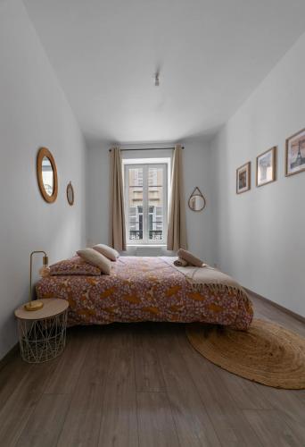 une chambre avec un grand lit avec une grande fenêtre dans l'établissement Le Ravy - Appartement design, 2 chambres, centre ville, à Vichy