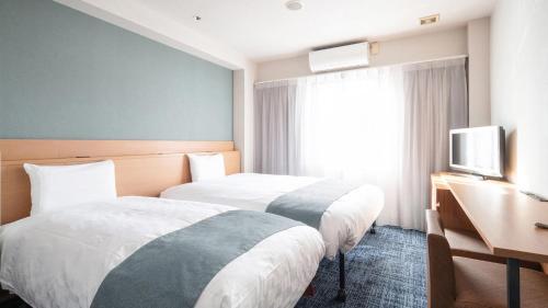 a hotel room with two beds and a television at Vessel Hotel Kurashiki in Kurashiki