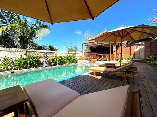 a swimming pool with a table and an umbrella at Puri Melati in Uluwatu