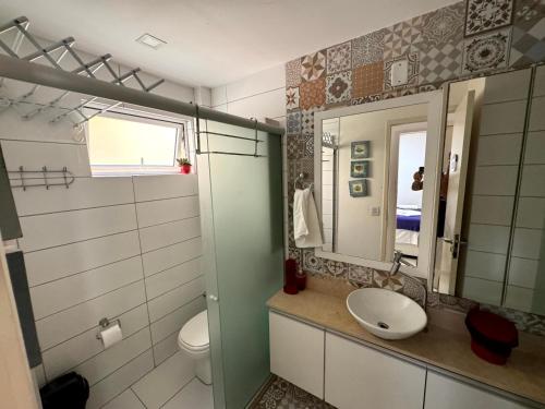 ein Badezimmer mit Waschbecken, Toilette und Spiegel in der Unterkunft Solar Agua Flats Elegance Flat in Pipa
