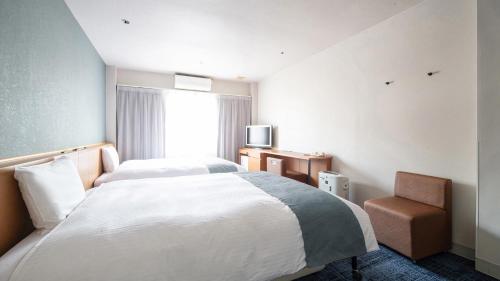 a hotel room with a bed and a chair at Vessel Hotel Kurashiki in Kurashiki