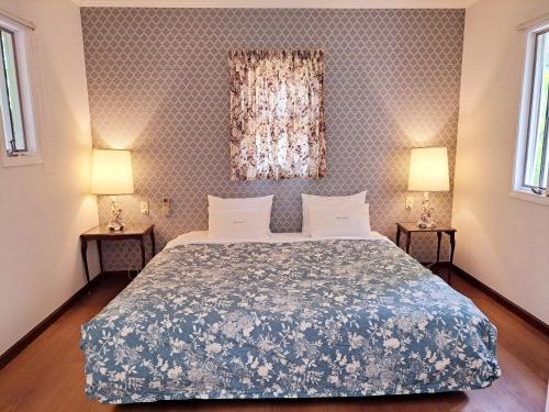 a bedroom with a bed and two lamps on two tables at ローズウッドガーデンアンドヴィラ in Nasu