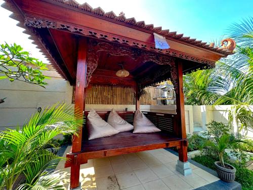 a wooden bench with white pillows on a porch at Puri Melati in Uluwatu
