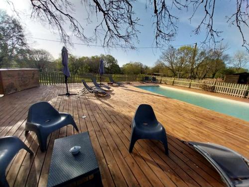une terrasse en bois avec des chaises et une piscine dans l'établissement Escale de la Jurade, à Rogues