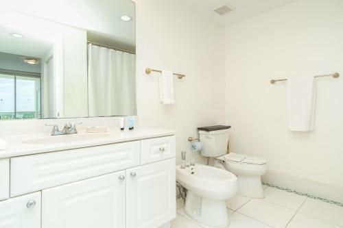 a white bathroom with a toilet and a sink at Golden Bay 1003 in Miami Beach