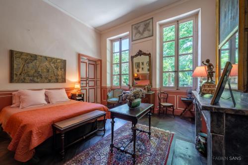 une chambre avec un lit, un bureau et des fenêtres dans l'établissement Maison d'Hôtes de La Rivière, à Pexiora