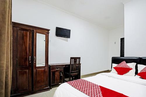 a bedroom with a bed and a wooden cabinet and a desk at Hotel O Kambang Iwak Area Near Kambang Iwak Park Formerly Kerangga in Palembang